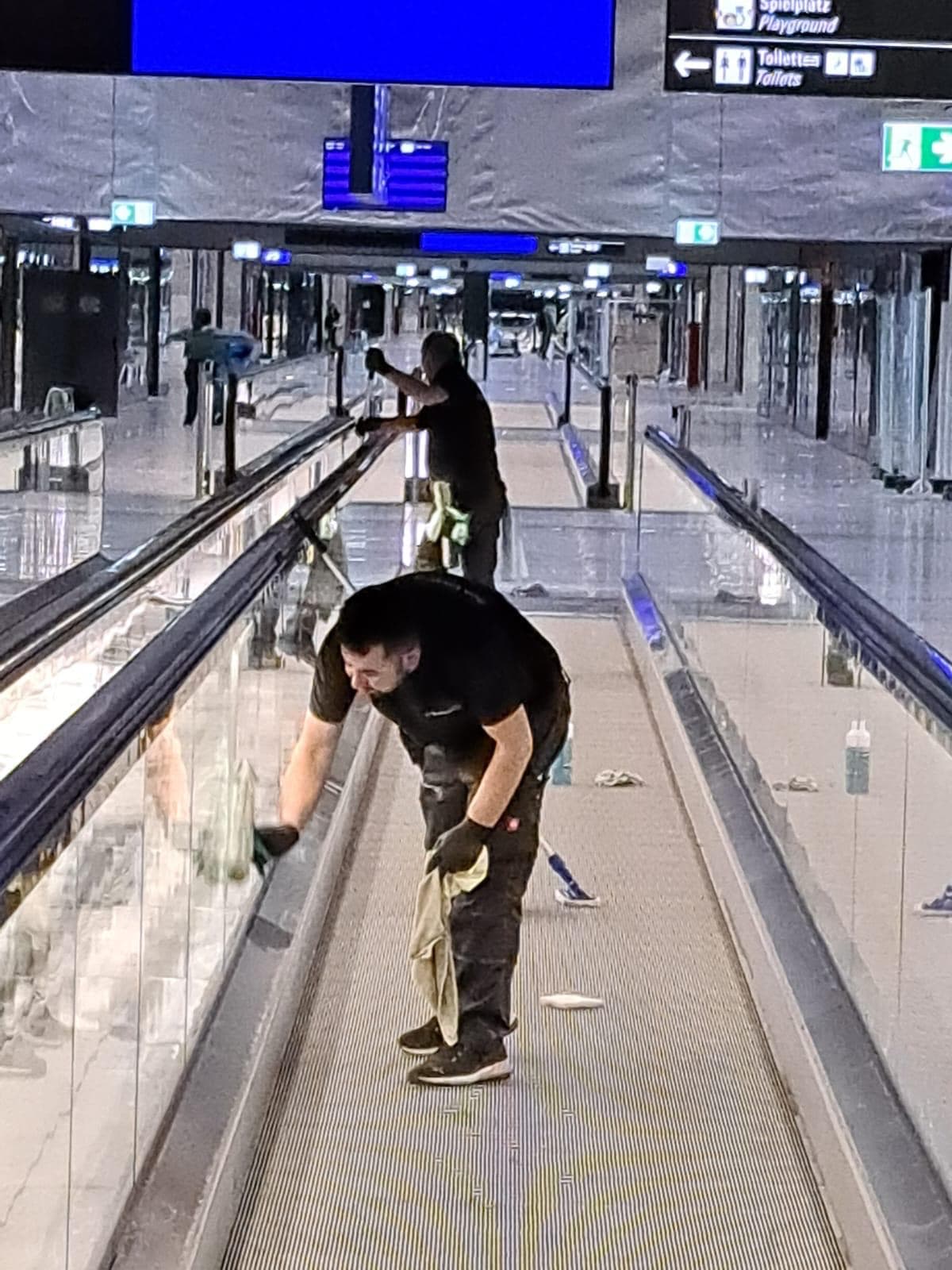 Cleanwerk-Team bei der Fensterreinigung auf einem Rollsteig im Terminal