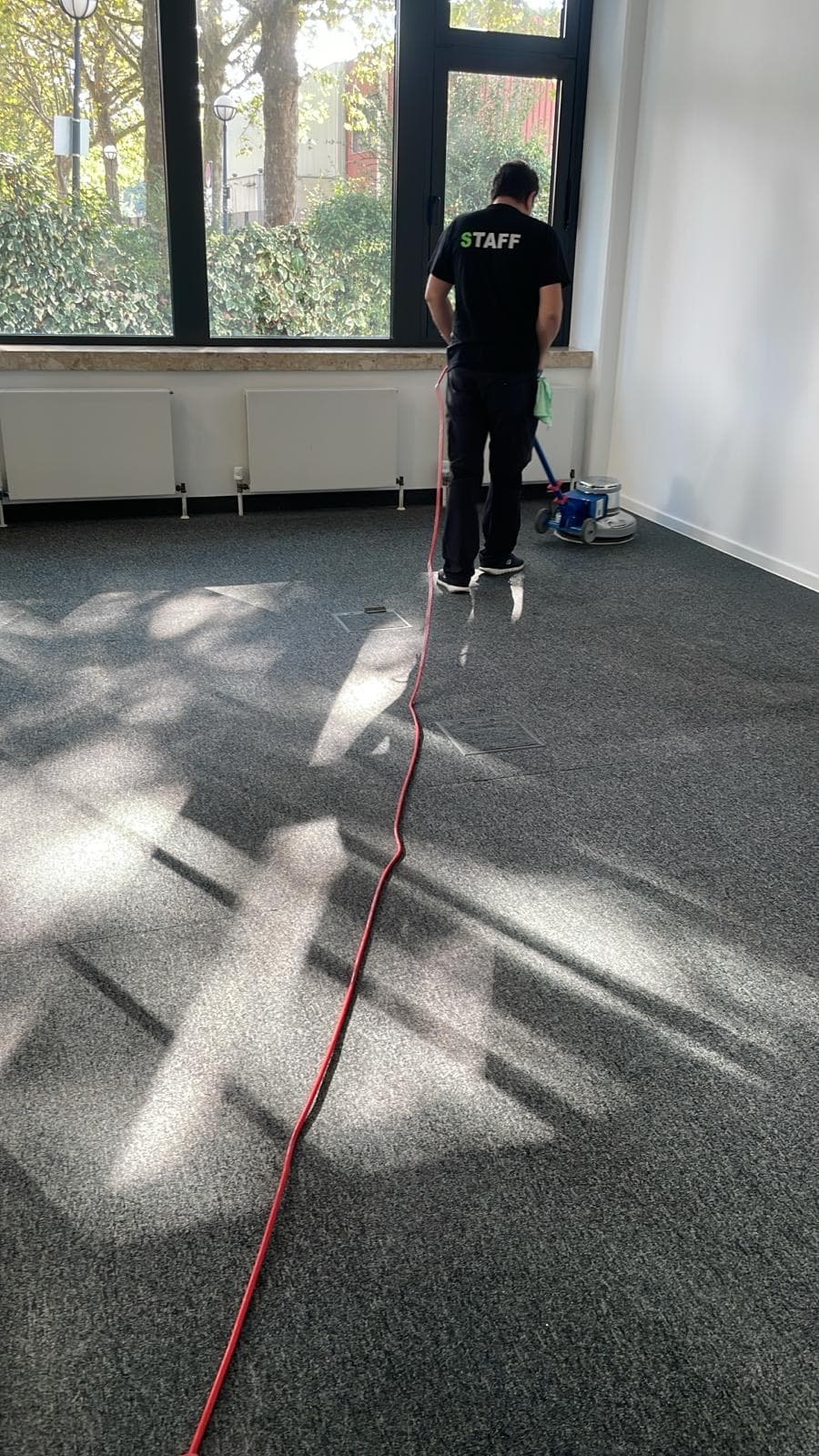 Cleanwerk-Mitarbeiter bei der Teppichshampoonierung mit der Reinigungsmaschine